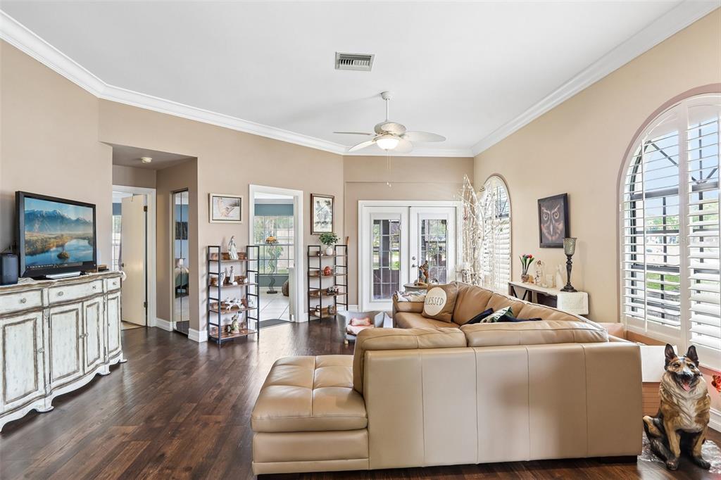 A living room features dark wood floors, a tan sectional sofa, and a television console — 3878 TANAGER PLACE, PALM HARBOR, FL