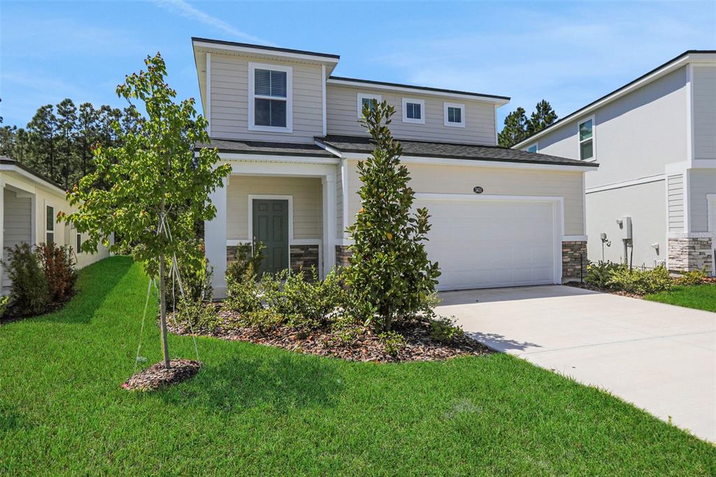 A two-story suburban house features beige siding, a stone-accented entryway, and a two-car garage — 3431 HUMPHREY STREET, GREEN COVE SPRINGS, FL