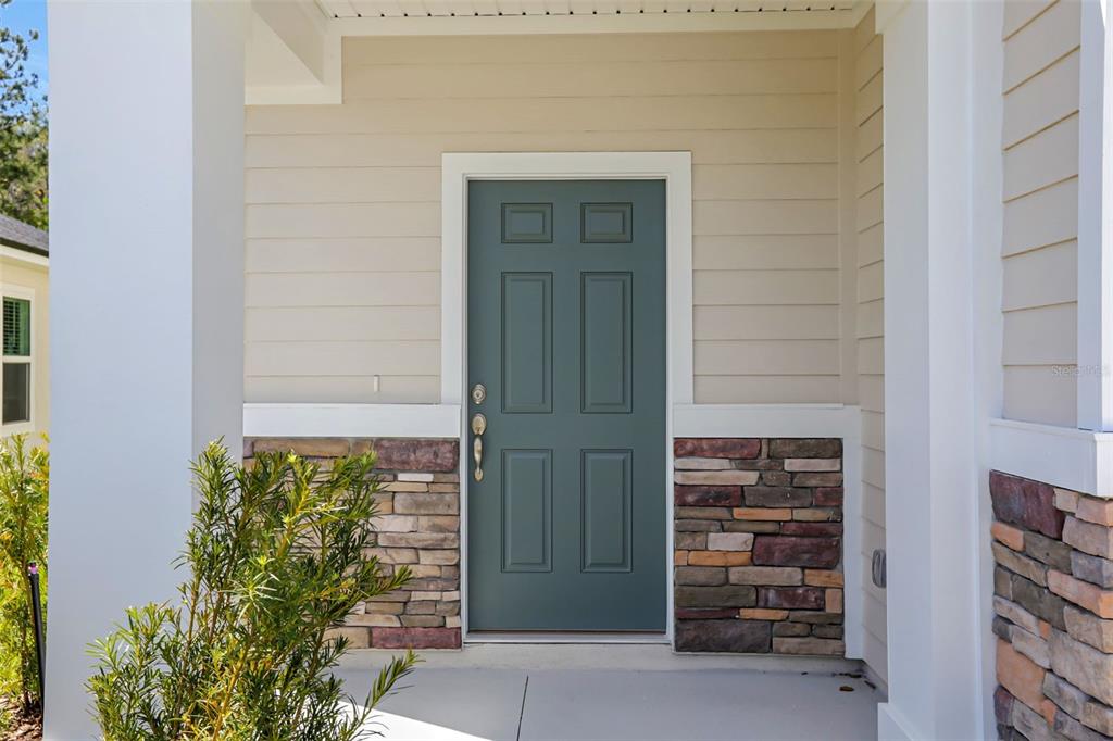 A teal front door is set into a tan house exterior with stone veneer accents — 3431 HUMPHREY STREET, GREEN COVE SPRINGS, FL