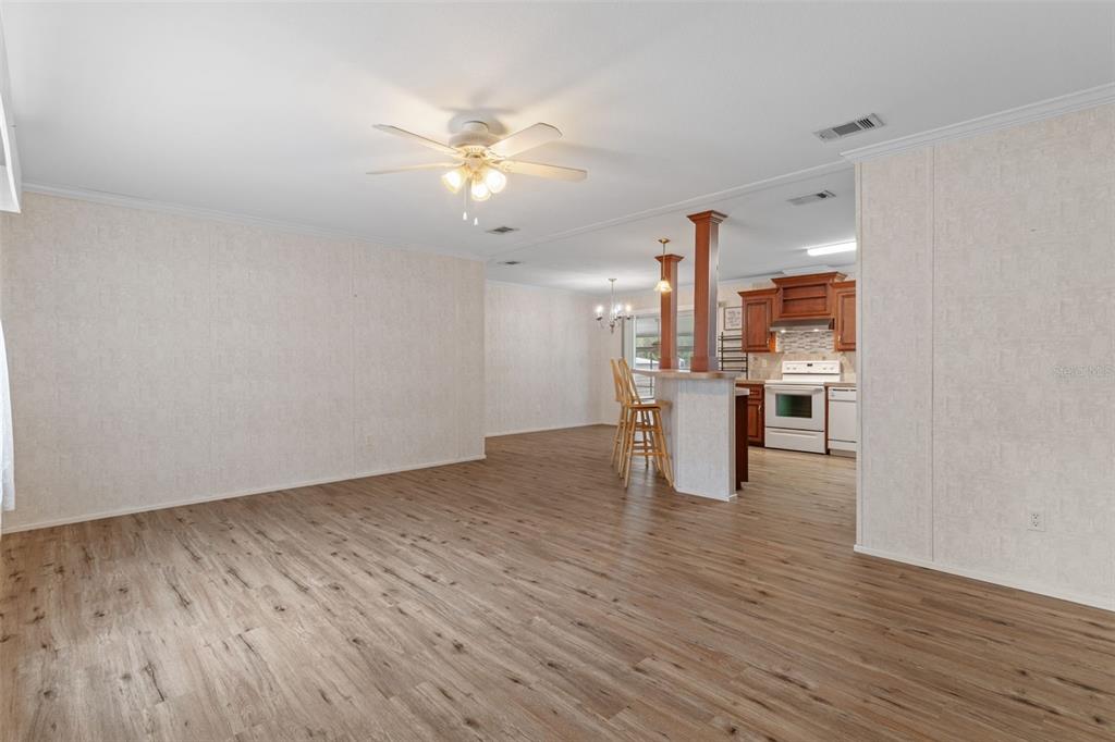 A living room with wood-look flooring opens to a kitchen featuring a breakfast bar — 5351 W ROLLING VIEW PLACE, LECANTO, FL