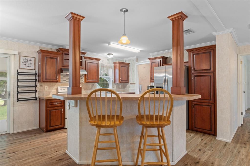 A kitchen features a breakfast bar with two wooden stools and two decorative support columns — 5351 W ROLLING VIEW PLACE, LECANTO, FL