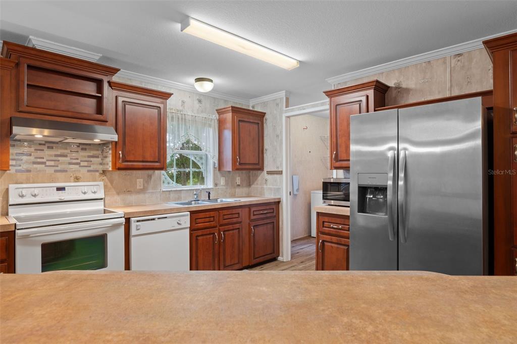 A kitchen features wood cabinets, stainless steel appliances, a tiled backsplash, and a laminate countertop — 5351 W ROLLING VIEW PLACE, LECANTO, FL