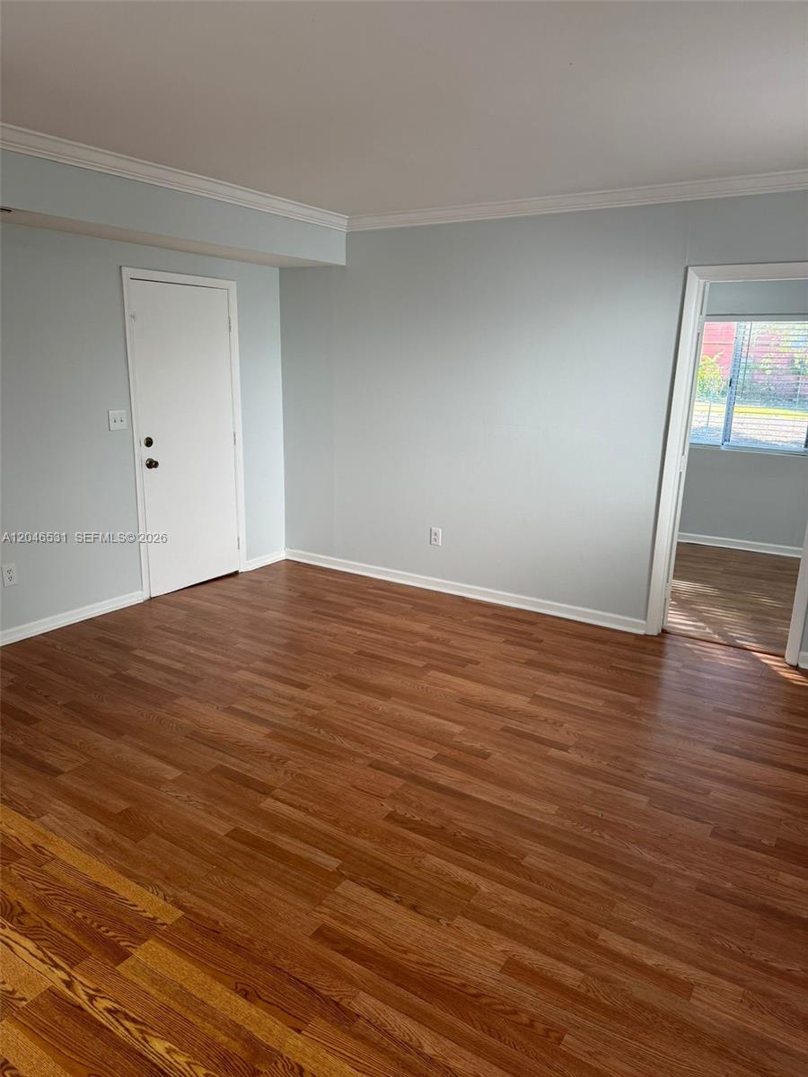 An empty room features light blue walls, wood-look flooring, a white door, and a doorway — 103 NW 6th Ave # 2, Miami FL 33128, MIAMI, FL