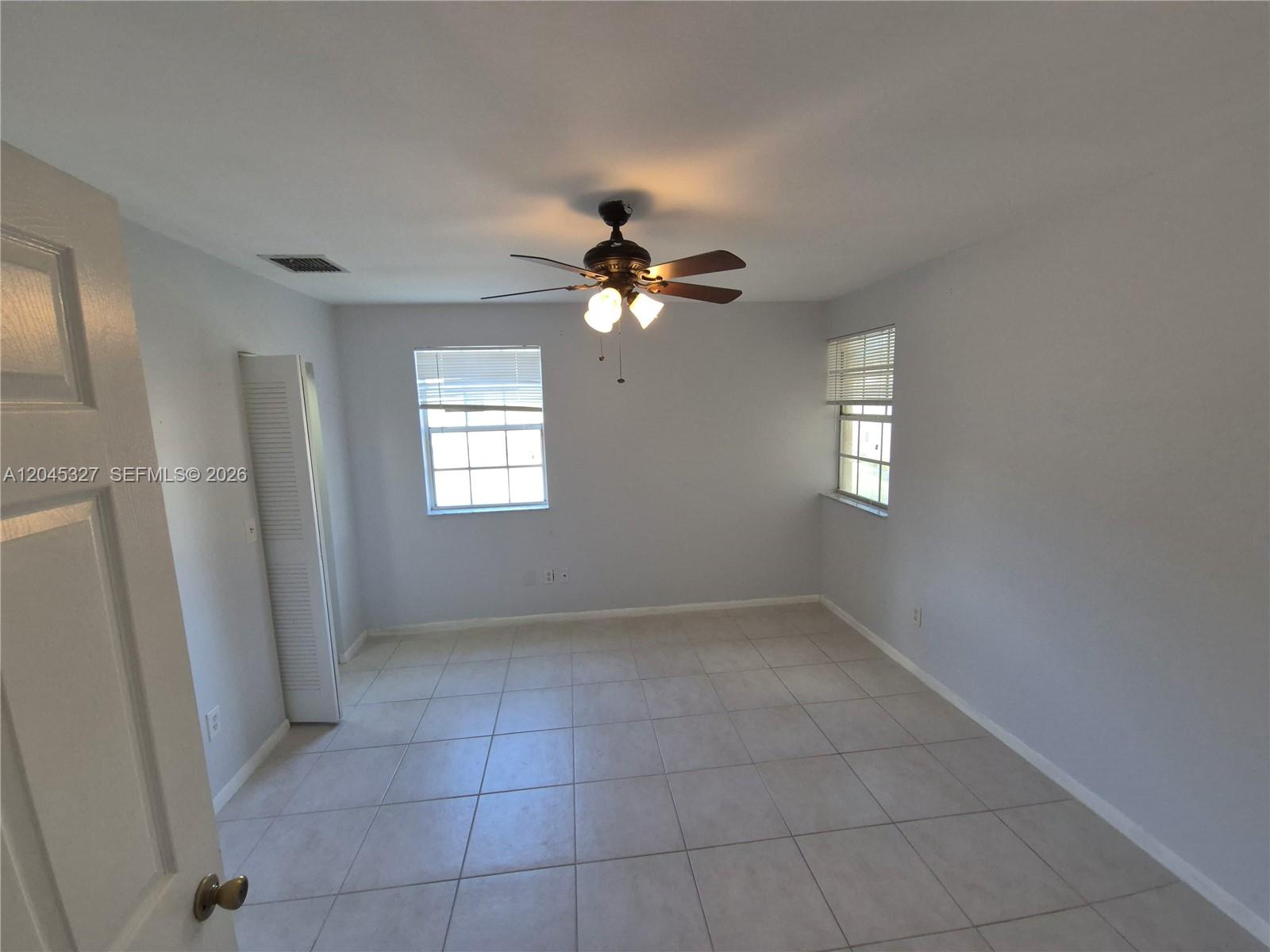 An empty bedroom features light gray walls, white tile flooring, and a ceiling fan — 18310 NW 68th Ave # P, Hialeah FL 33015, HIALEAH, FL