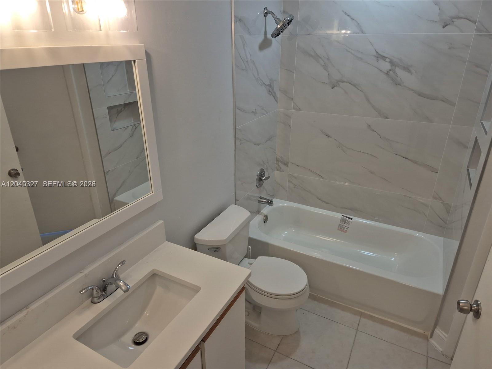 A bathroom features a white vanity, a toilet, and a bathtub with marble-look tile walls — 18310 NW 68th Ave # P, Hialeah FL 33015, HIALEAH, FL