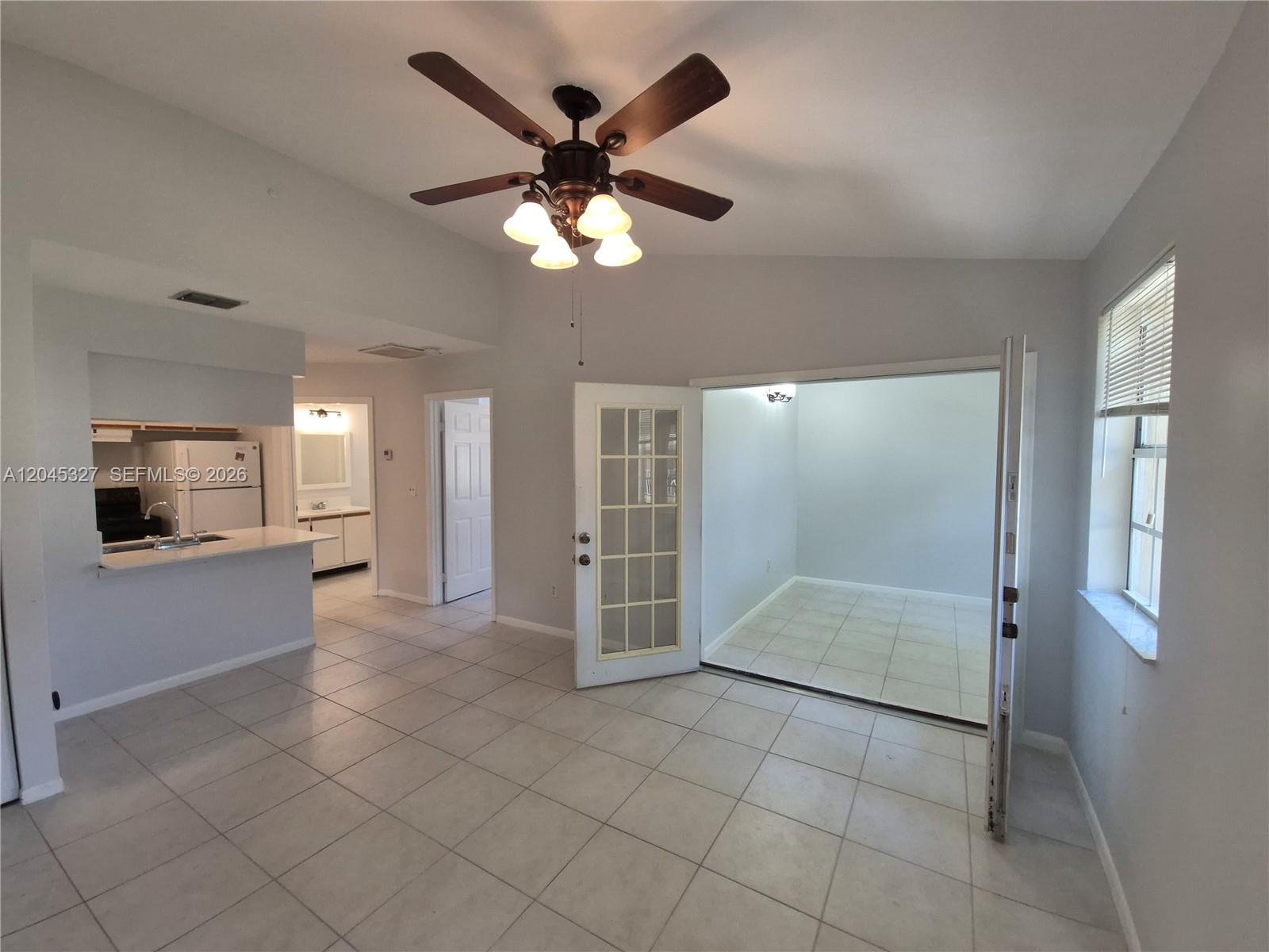 A tiled living area features a ceiling fan, a kitchen pass-through, and French doors — 18310 NW 68th Ave # P, Hialeah FL 33015, HIALEAH, FL