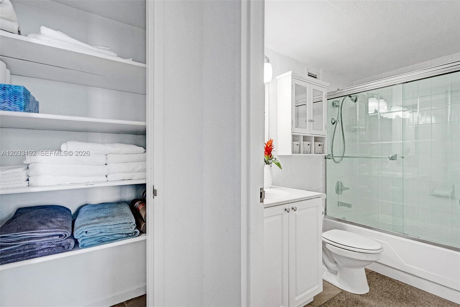 A bathroom features a white vanity, a glass-enclosed shower, and an adjacent open linen closet — 2501 S Ocean Dr, Hollywood FL 33019, HOLLYWOOD, FL