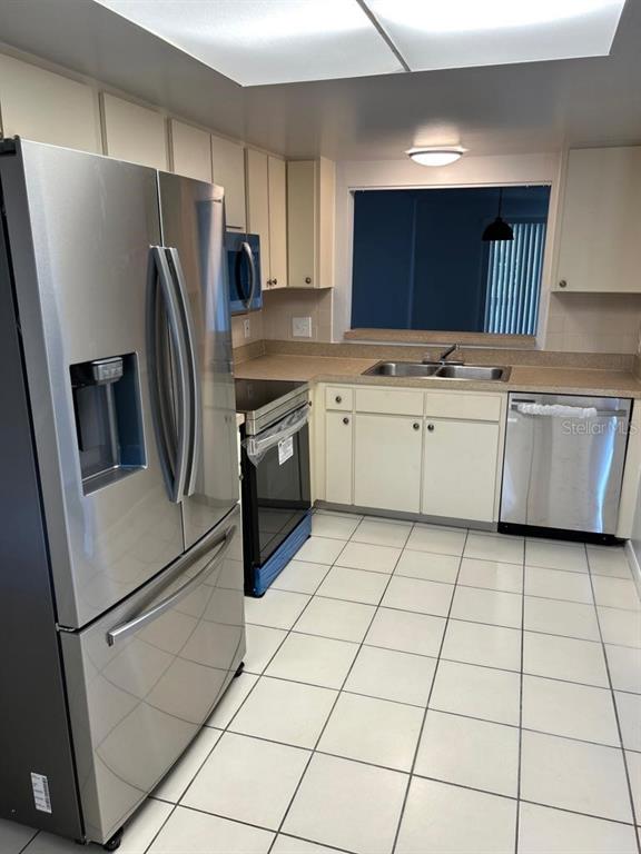 A kitchen with white cabinets, stainless steel appliances, and white tile flooring — 6338 NEWTOWN CIRCLE UNIT 38C5, TAMPA, FL
