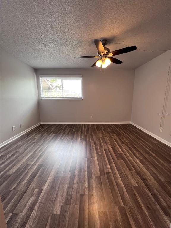 An empty room features wood-look flooring, light gray walls, and a ceiling fan with lights — 6338 NEWTOWN CIRCLE UNIT 38C5, TAMPA, FL