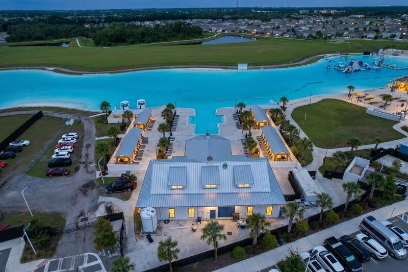 An aerial view shows a building with a metal roof beside a large turquoise lagoon — 17228 Star Banks Street, FL 33598, FL