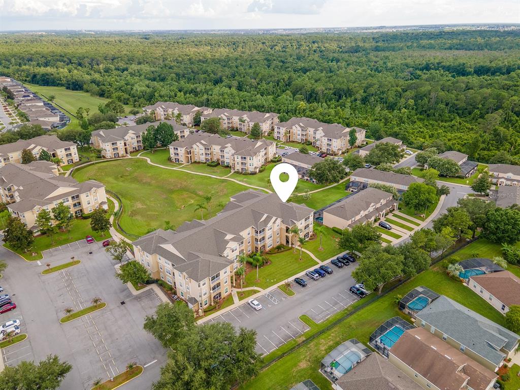 An aerial view shows a multi-story apartment complex surrounded by parking lots and green space — 8102 PRINCESS PALM LANE UNIT #305, KISSIMMEE, FL