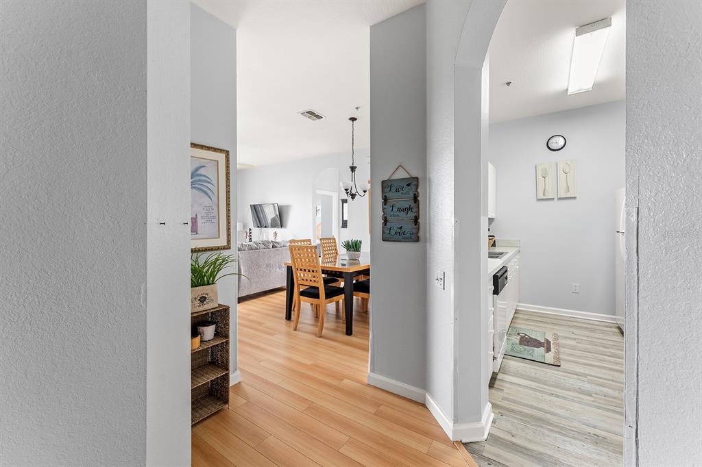 A view from a hallway looking into a dining area and a kitchen — 8102 PRINCESS PALM LANE UNIT #305, KISSIMMEE, FL