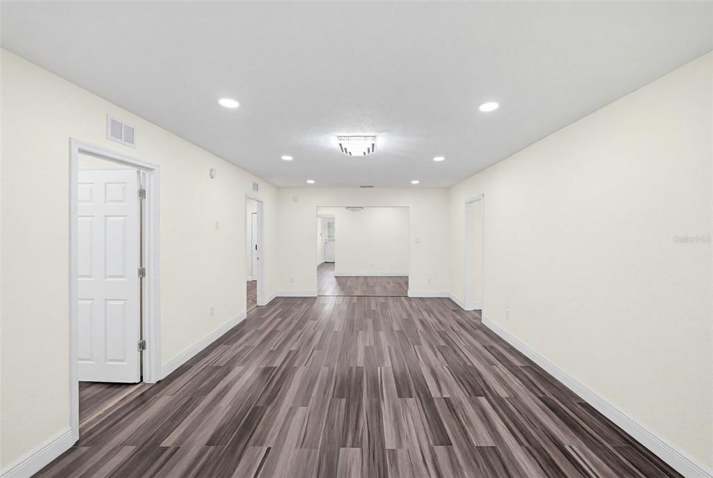 An empty room features light-colored walls, recessed lighting, and dark wood-look laminate flooring — 9402 N 12TH ST, TAMPA, FL
