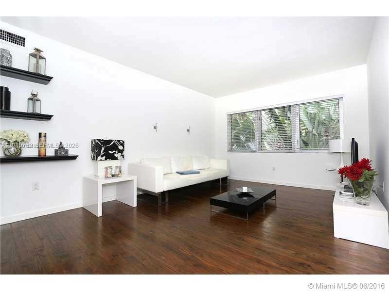 A living room features white walls, dark wood floors, a white sofa, and black shelving — 1616 Euclid Ave # 6, Miami Beach FL 33139, MIAMI BEACH, FL