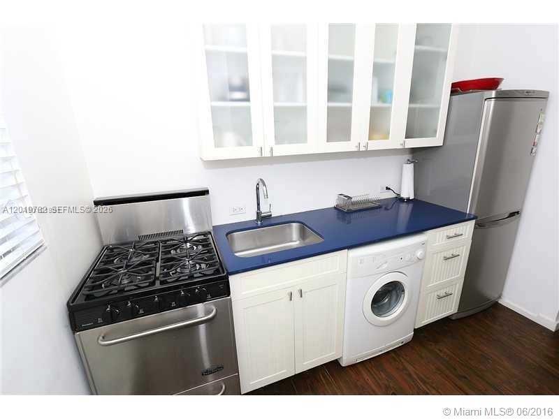 A small kitchen features white cabinets, a blue countertop, a gas stove, and a washer — 1616 Euclid Ave # 6, Miami Beach FL 33139, MIAMI BEACH, FL
