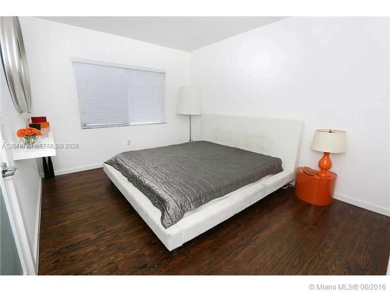 A bedroom features a white platform bed, dark wood flooring, and an orange bedside lamp — 1616 Euclid Ave # 6, Miami Beach FL 33139, MIAMI BEACH, FL