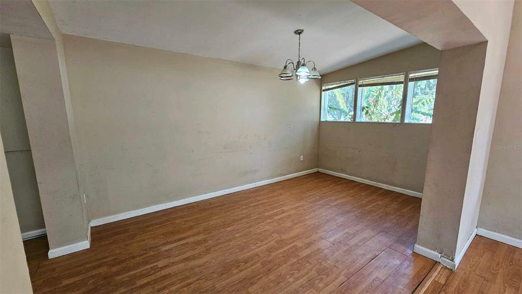 An empty dining room features wood-look flooring, beige walls, and a hanging light fixture — 1017 CYPRESS STREET, LEESBURG, FL