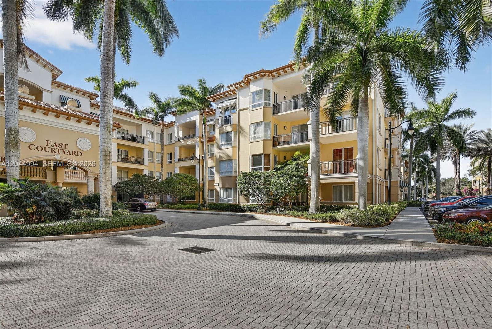 A multi-story residential building with palm trees and a paved driveway in the foreground — WESTON, FL