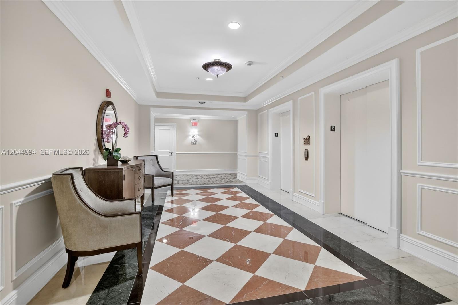 A hallway features a checkered floor, two elevators, and two armchairs near a console table — WESTON, FL