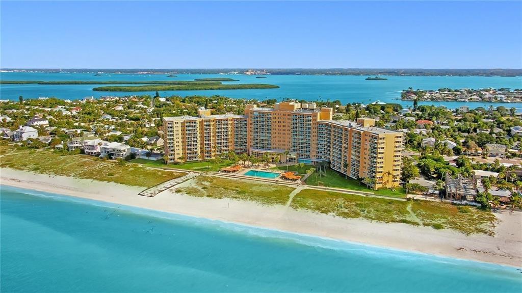An aerial view of a large beachfront condominium complex surrounded by residential homes and water — 880 MANDALAY AVENUE UNIT C801, CLEARWATER BEACH, FL