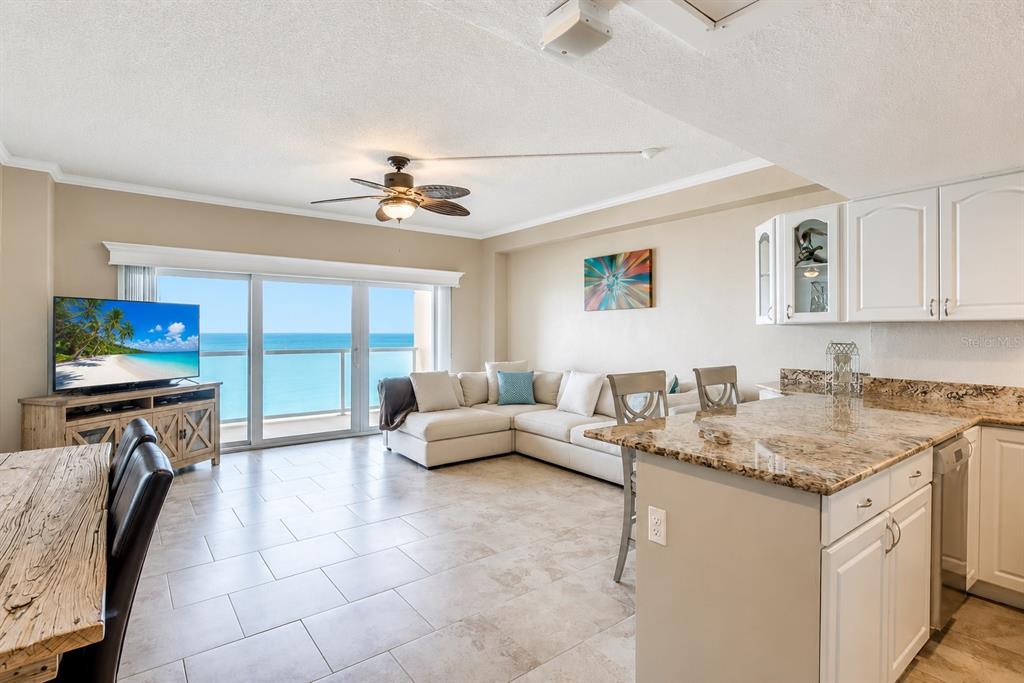 An open-concept living area features a kitchen with granite countertops and a balcony overlooking the ocean — 880 MANDALAY AVENUE UNIT C801, CLEARWATER BEACH, FL