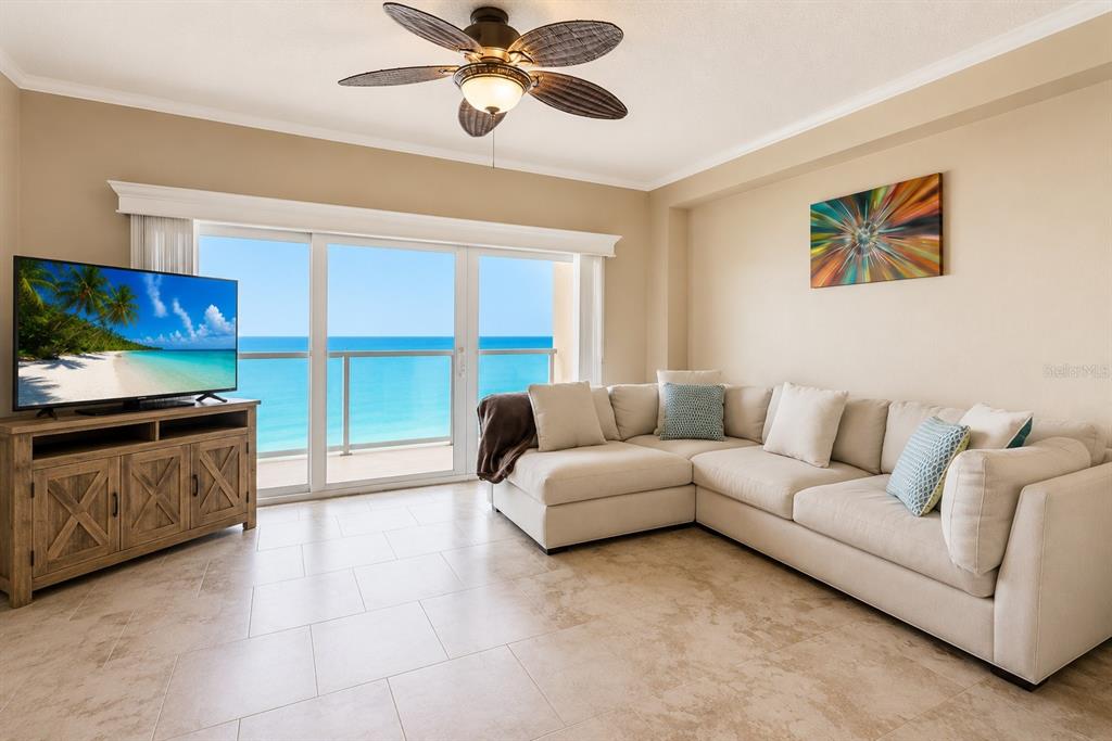 A living room features a beige sectional sofa, a wooden media console, and ocean views — 880 MANDALAY AVENUE UNIT C801, CLEARWATER BEACH, FL