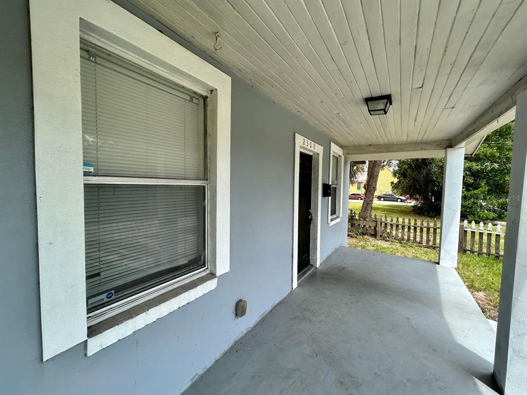 A covered front porch with gray walls, a white door, and a window with blinds — 2308 E 15TH AVENUE, TAMPA, FL