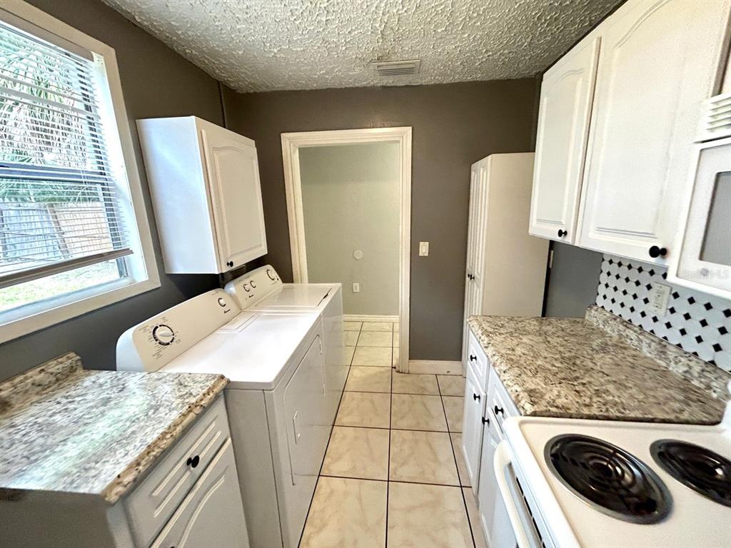 A laundry area with white appliances, granite countertops, and white cabinets in a kitchen space — 2308 E 15TH AVENUE, TAMPA, FL