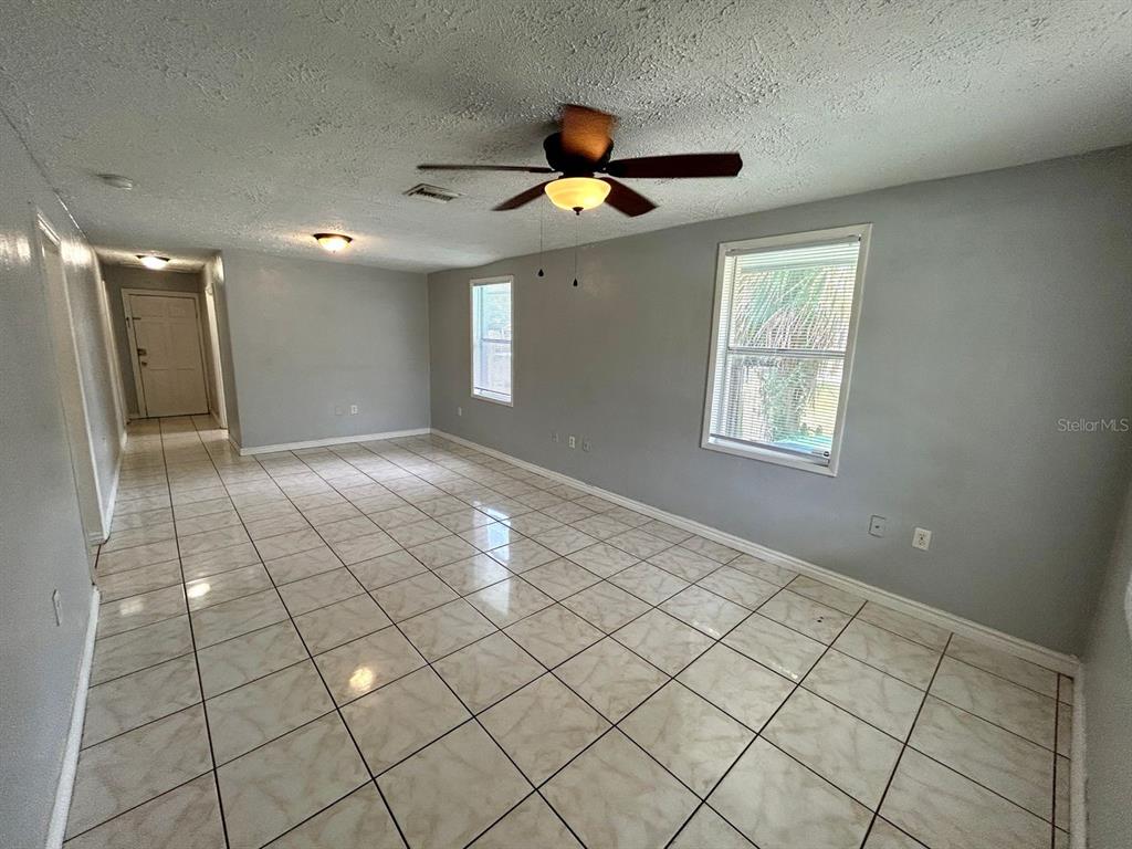 An empty room features light gray walls, a ceiling fan, and beige tiled flooring — 2308 E 15TH AVENUE, TAMPA, FL