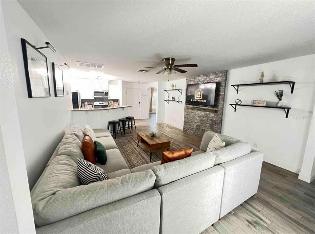 A living room features a large sectional sofa, a stone fireplace with a television, and an open kitchen — 660 SWALLOWTAIL DRIVE, HAINES CITY, FL