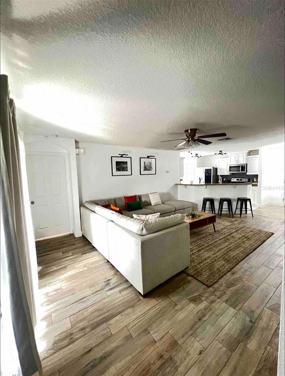 A living room with a sectional sofa, wood-look tile flooring, and an open kitchen — 660 SWALLOWTAIL DRIVE, HAINES CITY, FL