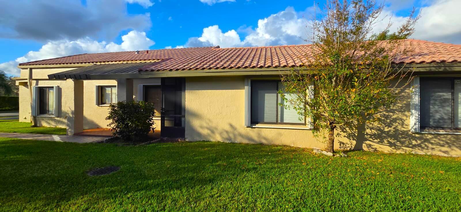 A single-story house with a tan stucco exterior, tile roof, and a small front yard — 566 Village Lake Drive, Weston FL 33326, WESTON, FL
