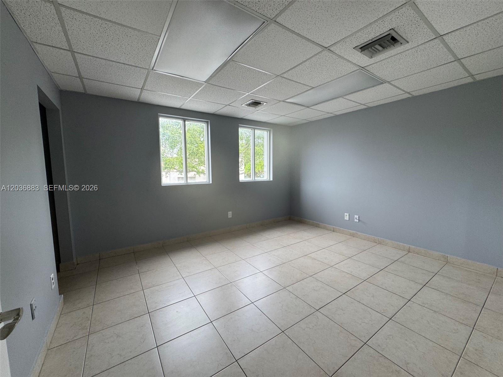 An empty office room features gray walls, tiled flooring, and a drop ceiling with lights — 13026 SW 128th St # 9, Miami FL 33186, MIAMI, FL