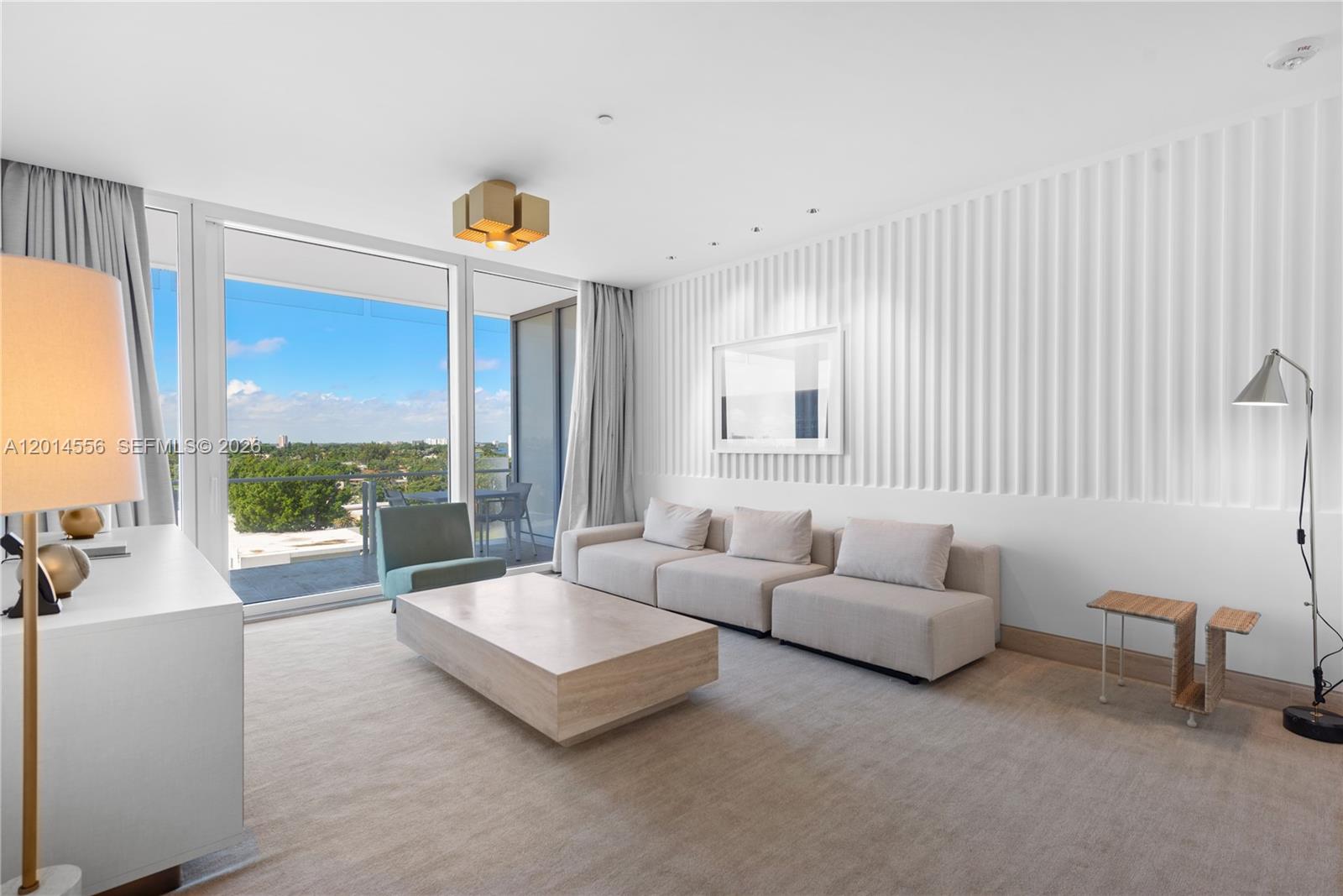 A modern living room features a beige sofa, stone coffee table, and floor-to-ceiling windows — 9111 Collins Ave # 712, Surfside FL 33154, SURFSIDE, FL