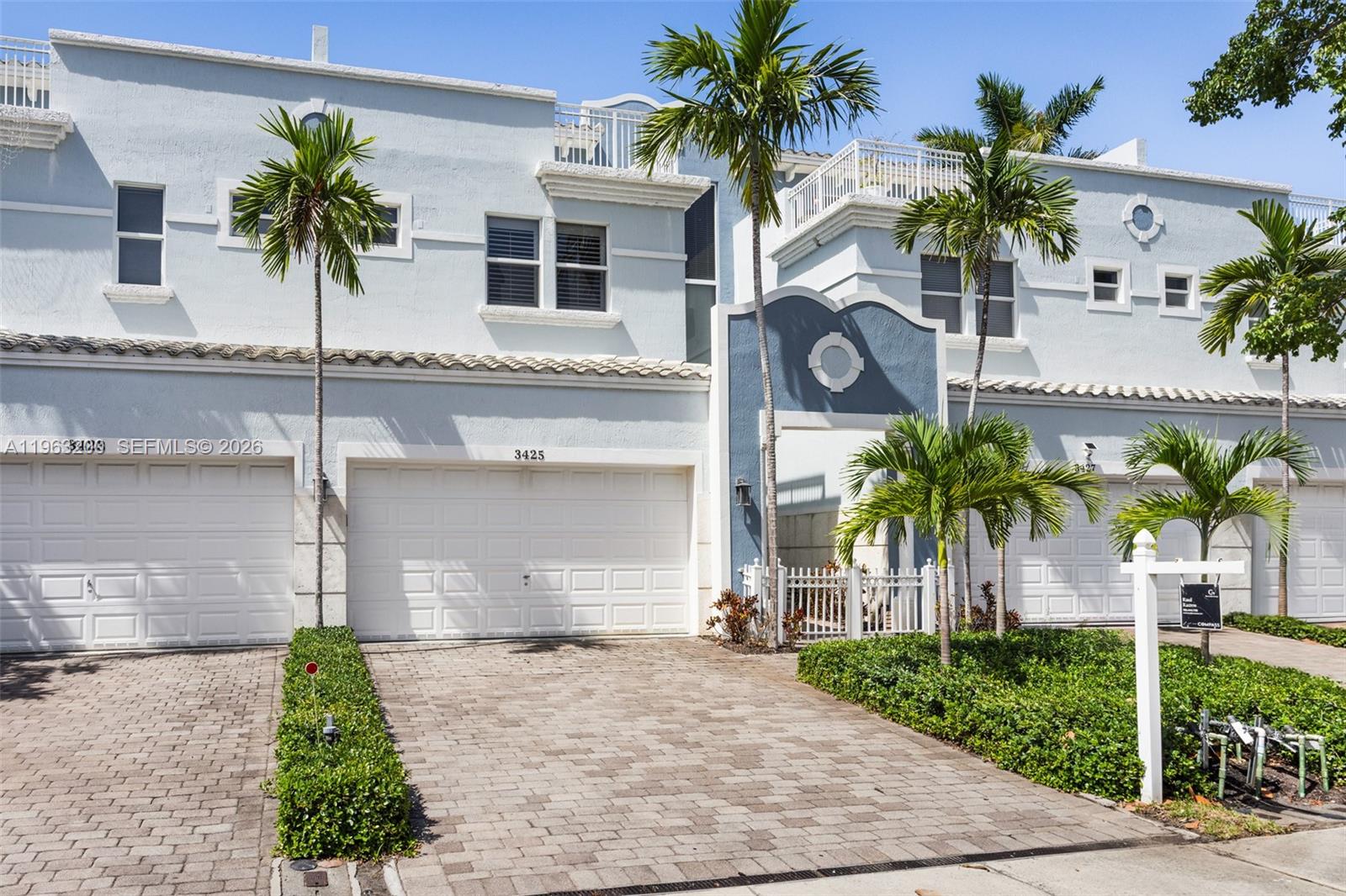 A multi-story townhouse features a light blue exterior, a two-car garage, and palm trees — 3425 NORFOLK ST, Pompano Beach FL 33062, POMPANO BEACH, FL