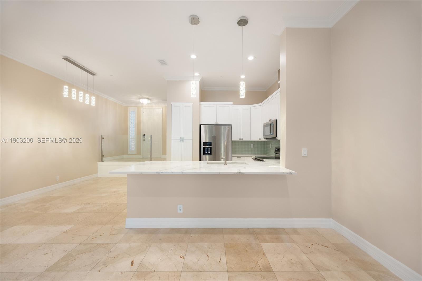 A kitchen features white cabinets, a marble-topped island, and light-colored tile flooring — 3425 NORFOLK ST, Pompano Beach FL 33062, POMPANO BEACH, FL