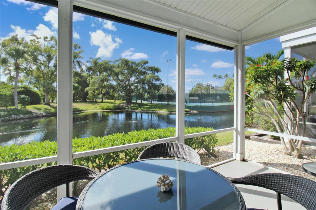 A screened-in patio overlooks a pond and tennis courts on a sunny day — 1260 SIESTA BAYSIDE DRIVE UNIT 1260-A, SARASOTA, FL