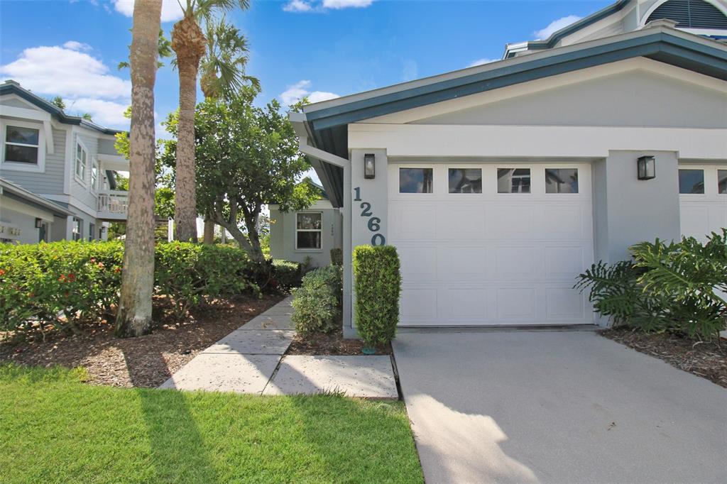 A view of a house exterior featuring a white garage door and a paved walkway — 1260 SIESTA BAYSIDE DRIVE UNIT 1260-A, SARASOTA, FL