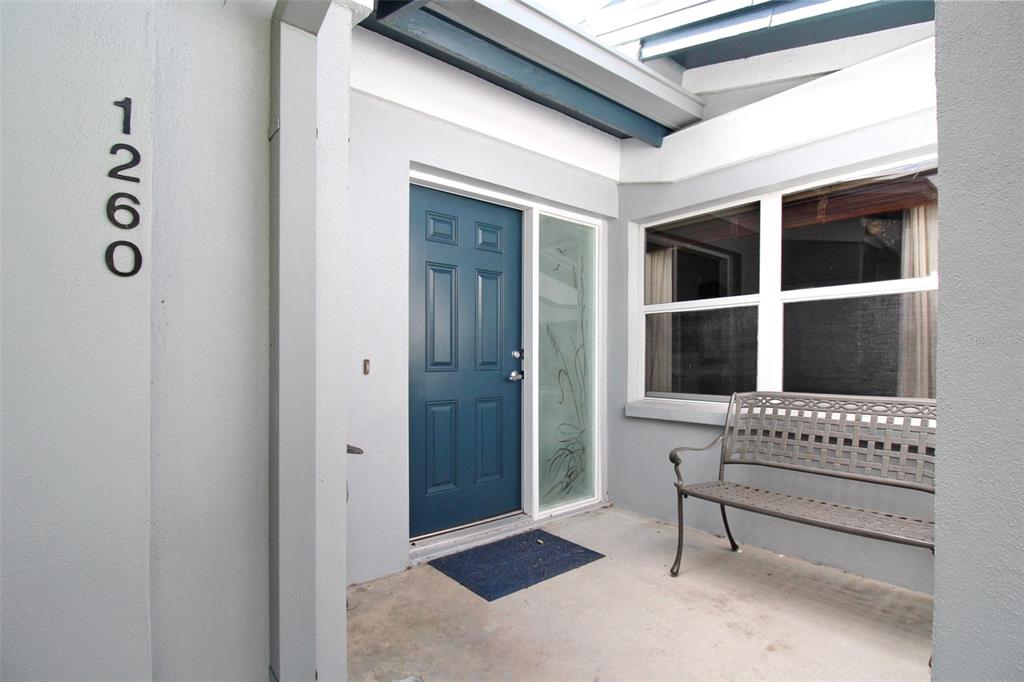 A blue front door with a side window and a metal bench on a porch — 1260 SIESTA BAYSIDE DRIVE UNIT 1260-A, SARASOTA, FL