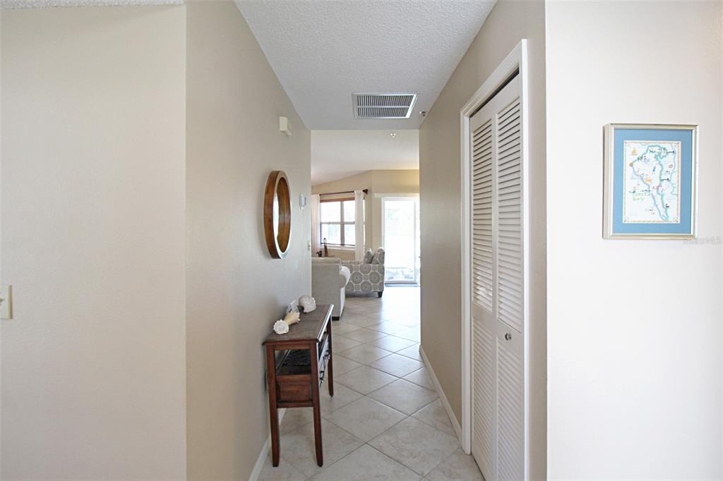 A tiled hallway leads past a wooden console table toward a bright living area — 1260 SIESTA BAYSIDE DRIVE UNIT 1260-A, SARASOTA, FL