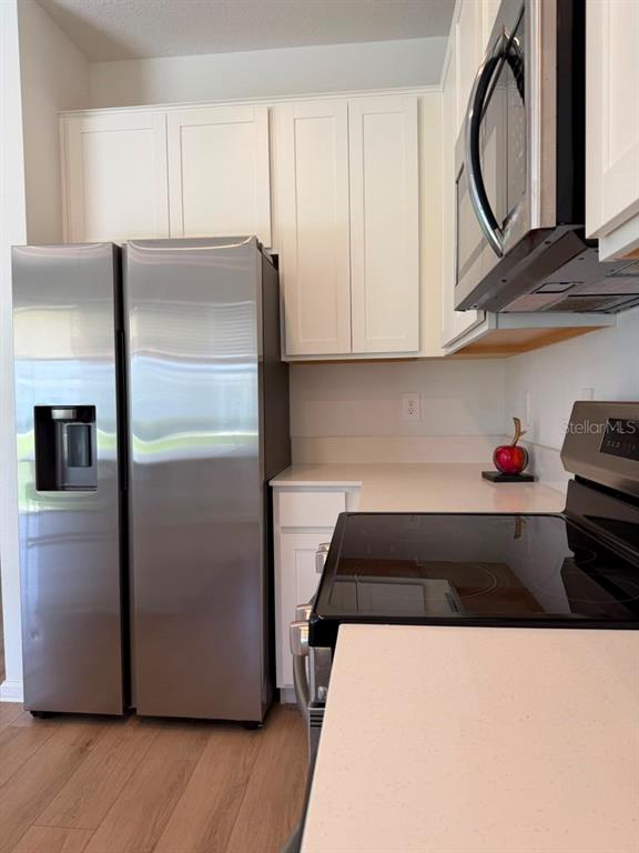 A kitchen features white cabinets, stainless steel appliances, and light-colored countertops — 2954 SAVOIR AVENUE, DAVENPORT, FL
