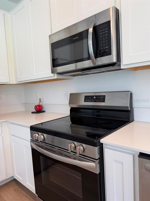 A kitchen features white cabinets, a stainless steel microwave, and a stainless steel electric range — 2954 SAVOIR AVENUE, DAVENPORT, FL
