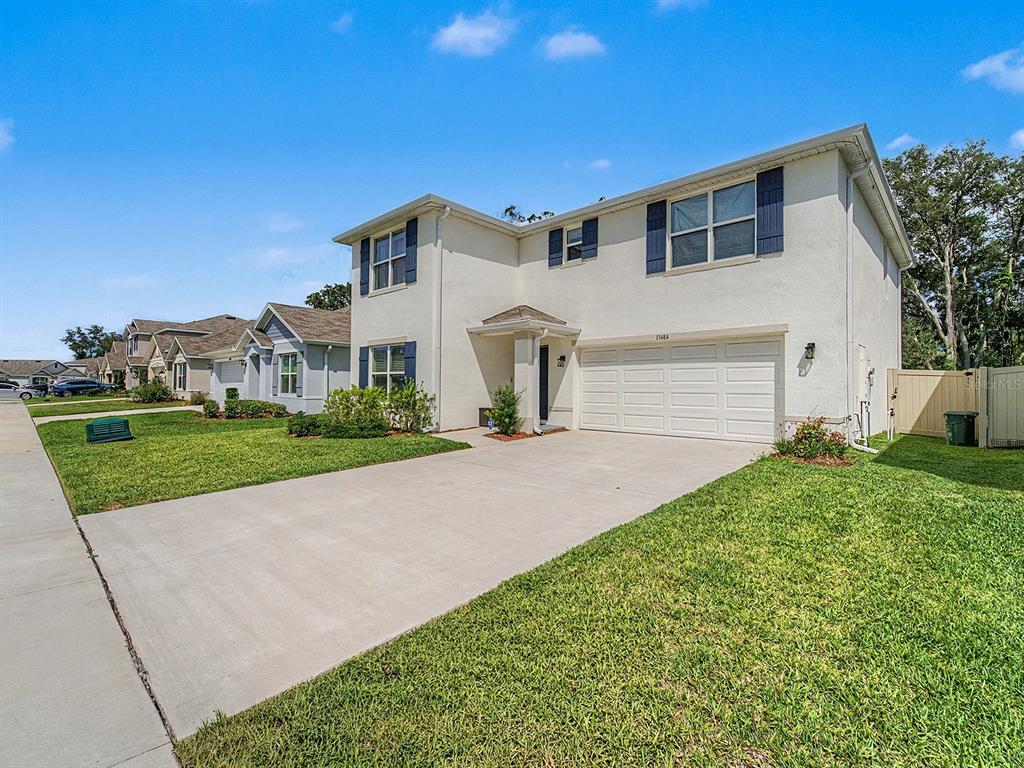 A two-story house with a white stucco exterior, a two-car garage, and a concrete driveway — 13484 MYLION WAY, SPRING HILL, FL