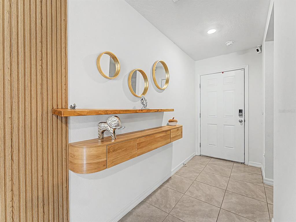 A modern entryway features a floating wooden console, a matching shelf, and three circular mirrors — 13484 MYLION WAY, SPRING HILL, FL