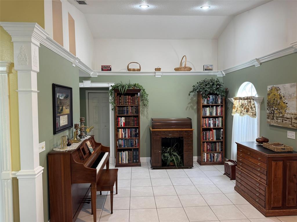 A room with sage green walls, tile flooring, a piano, bookshelves, and a roll-top desk — 9814 OSLIN STREET, TAMPA, FL