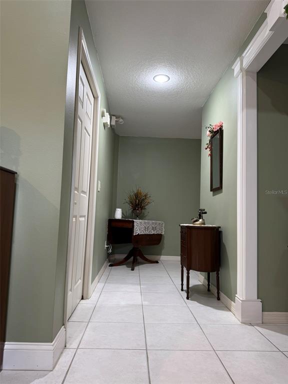 A hallway with light green walls, white tile flooring, and two pieces of wooden furniture — 9814 OSLIN STREET, TAMPA, FL
