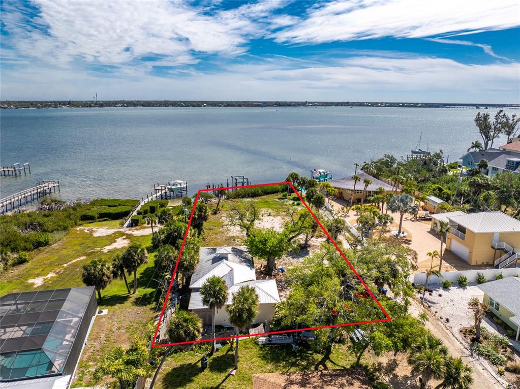 An aerial view shows a waterfront property with a house and trees outlined in red — 6039 MANASOTA KEY ROAD, ENGLEWOOD, FL