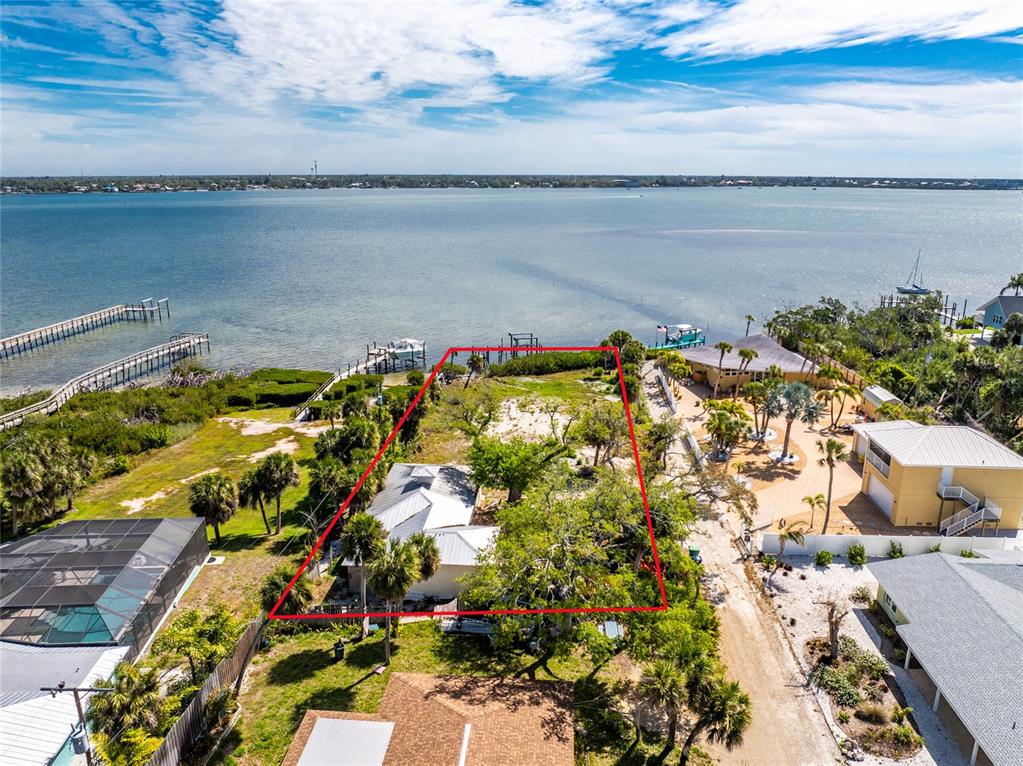 An aerial view shows a waterfront residential lot outlined in red with a house and trees — 6039 MANASOTA KEY ROAD, ENGLEWOOD, FL