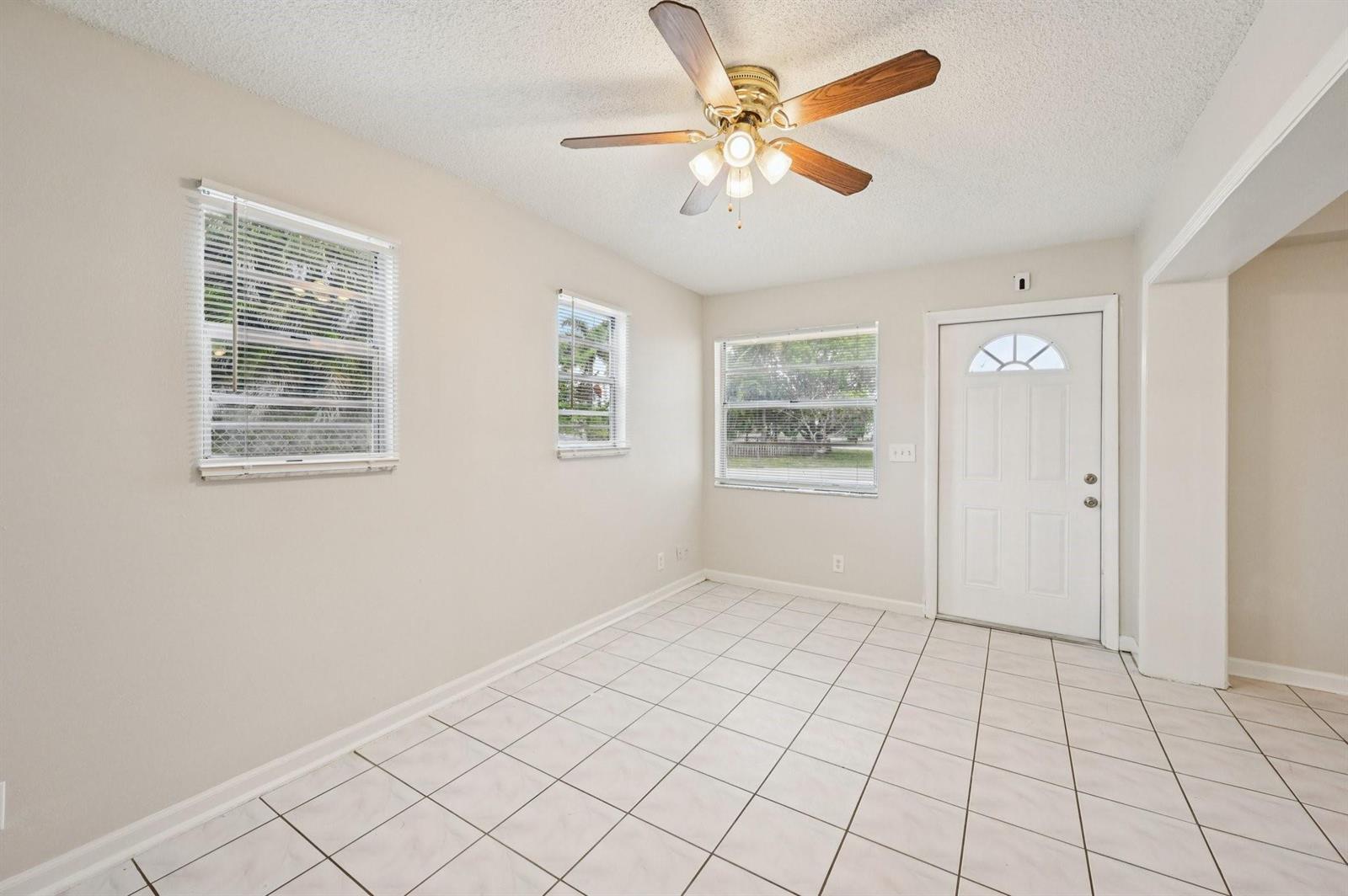 An empty room with white tiled floors, three windows, and a ceiling fan — 5618 Cinnamon Drive, West Palm Beach FL 33415, WEST PALM BEACH, FL