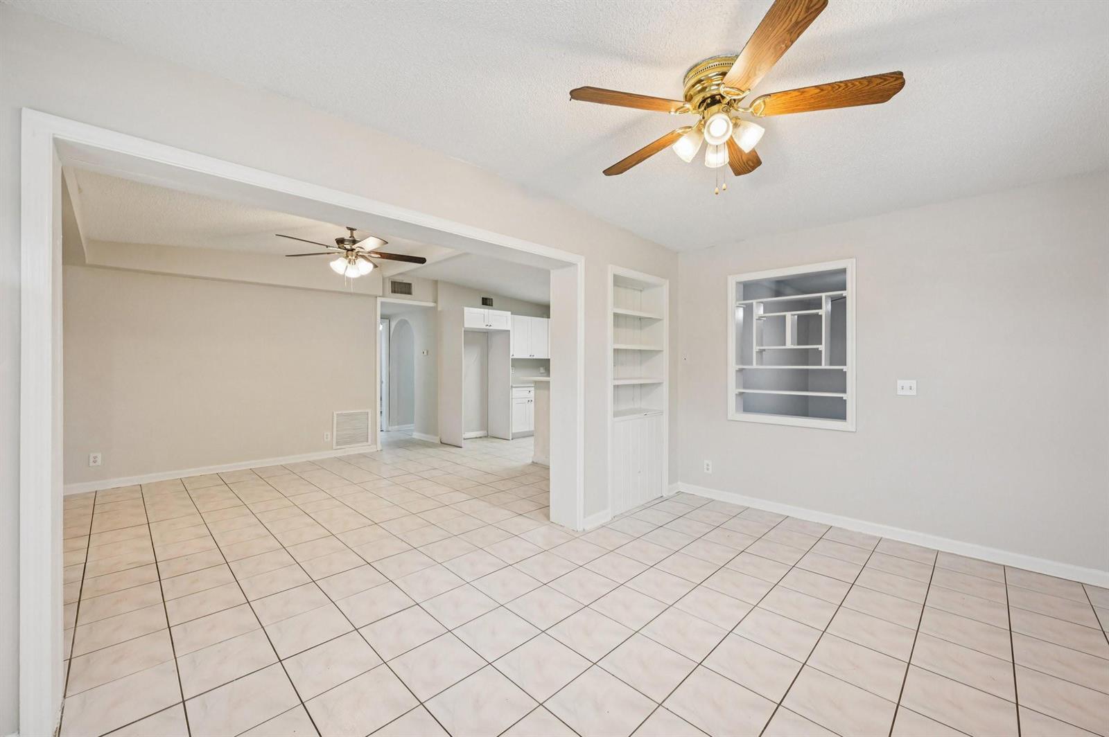 An open-concept living area features light-colored tile flooring, two ceiling fans, and built-in shelving — 5618 Cinnamon Drive, West Palm Beach FL 33415, WEST PALM BEACH, FL
